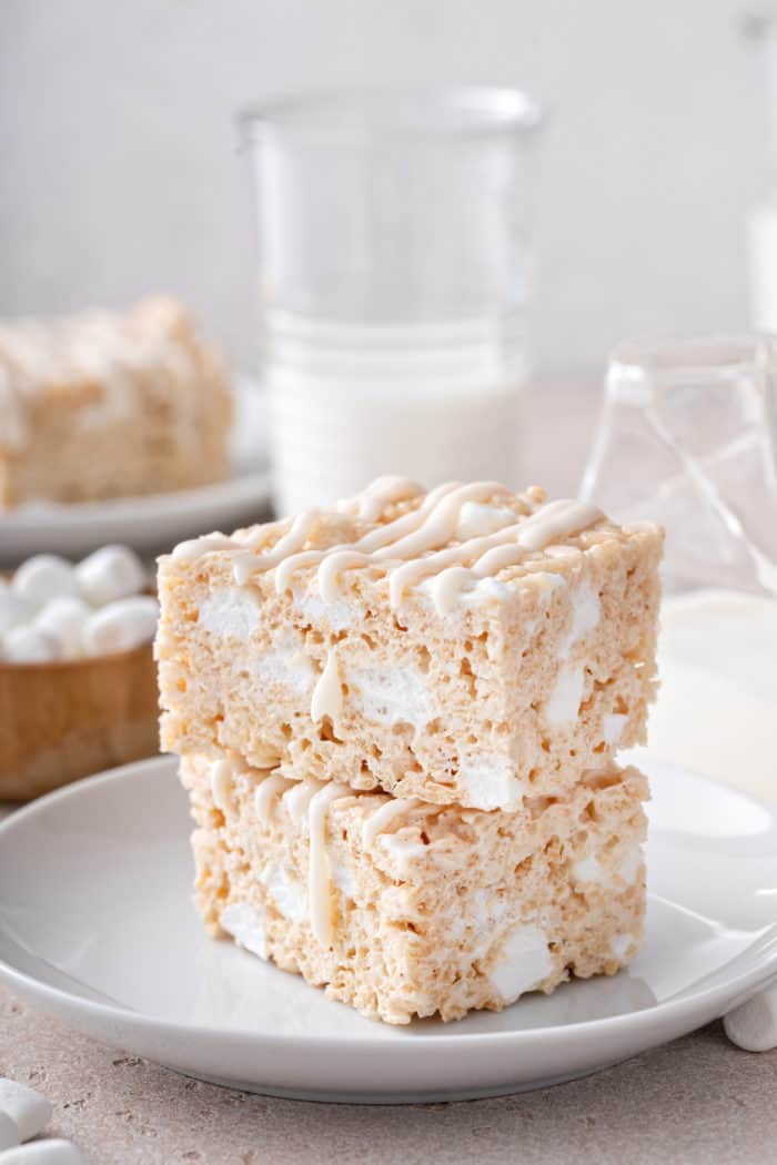 Two brown butter rice krispie treats stacked on a white plate.