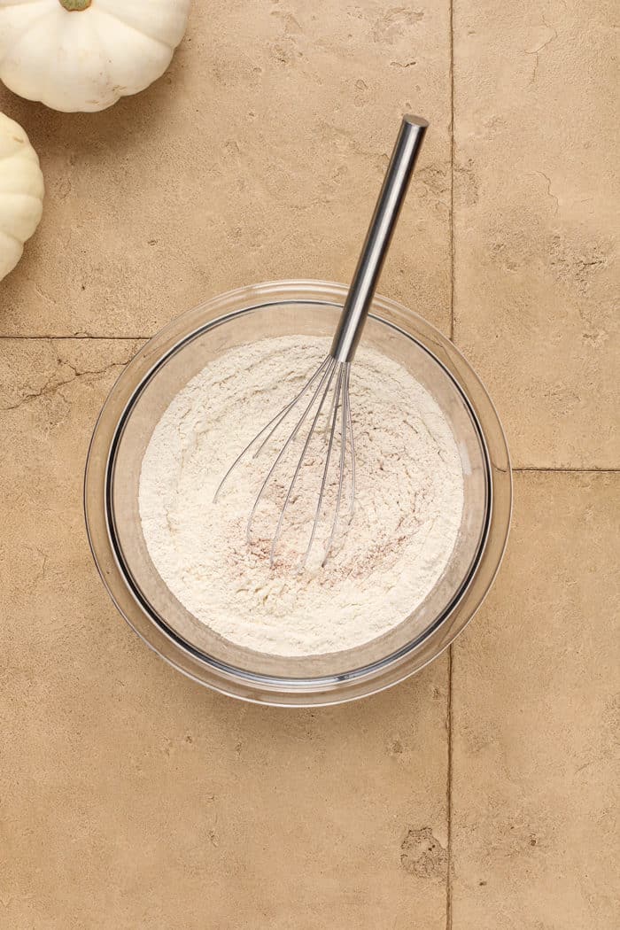 Whisk stirring together dry ingredients for muffins in a glass mixing bowl