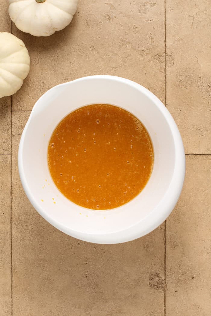 Wet ingredients for pumpkin muffins in a white mixing bowl