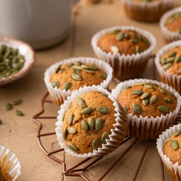 Pumpkin muffins topped with pumpkin seeds on a wire rack