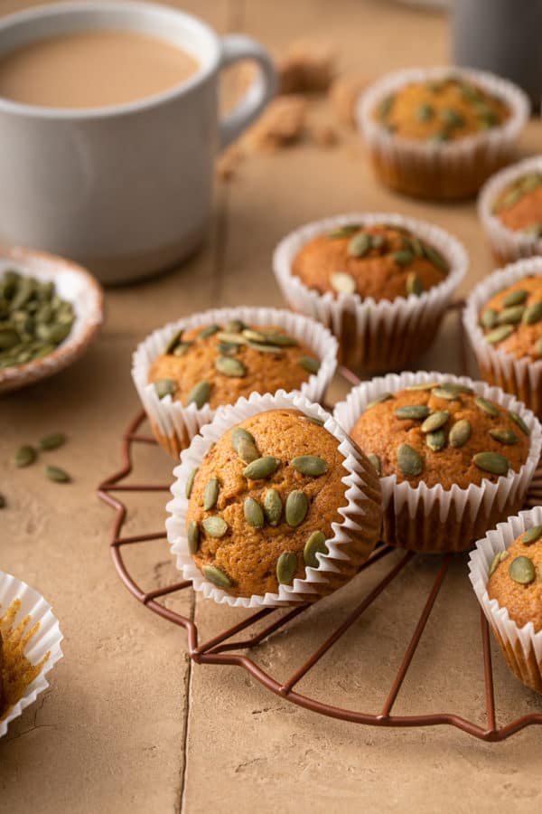 Pumpkin muffins topped with pumpkin seeds on a wire rack