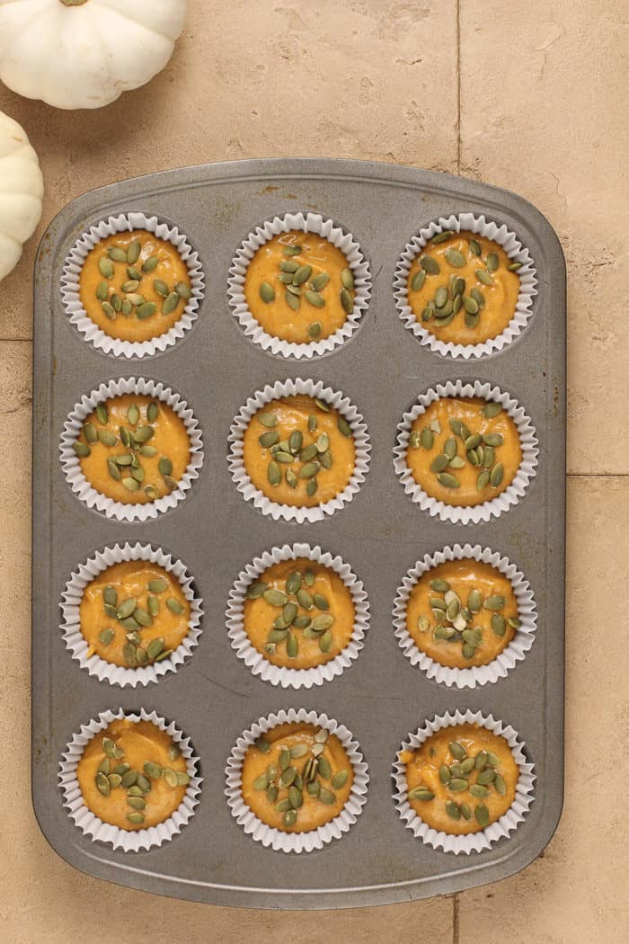Batter for pumpkin muffins divided into a lined muffin tin, ready to bake