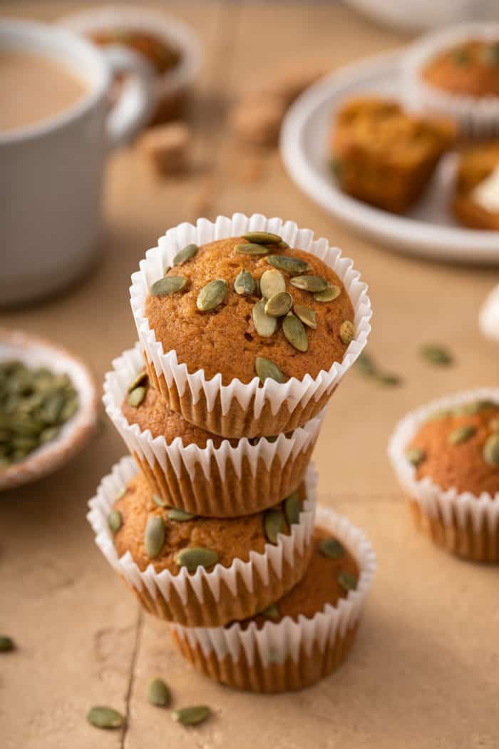 Four pumpkin muffins stacked on a tile counter