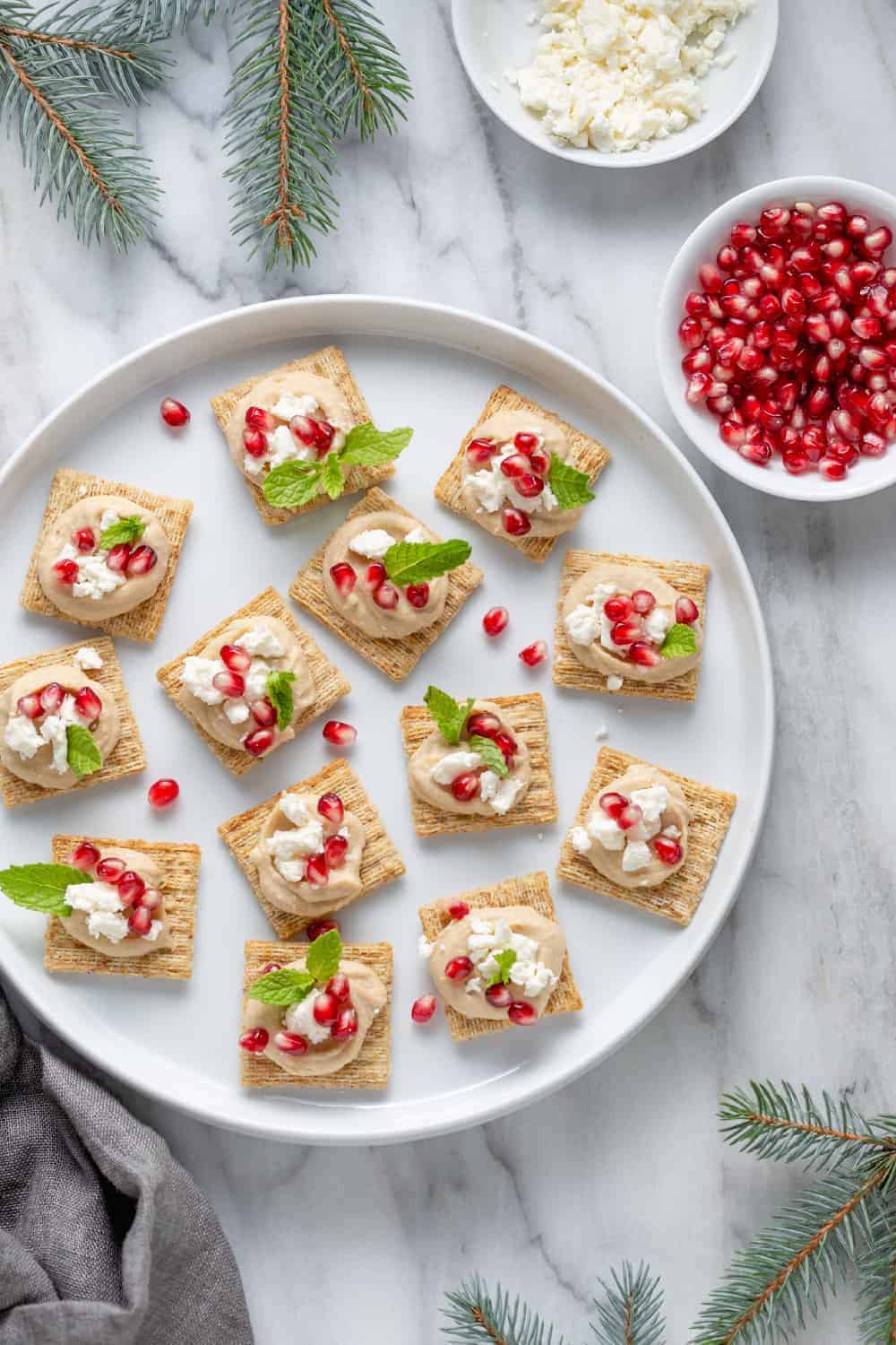 Hummus-Pomegranate TRISCUIT Toppers use just a handful of ingredients – hummus, feta and pomegranate seeds – to create a fun party snack for all ages!