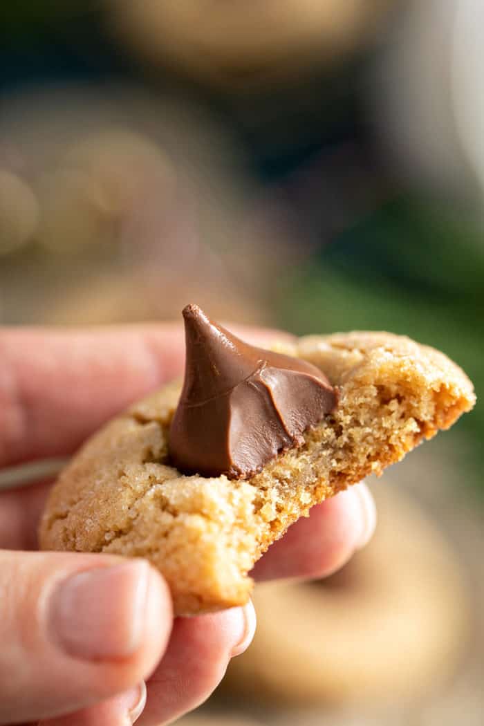 Hand holding up a peanut butter blossom with a bite taken out of it