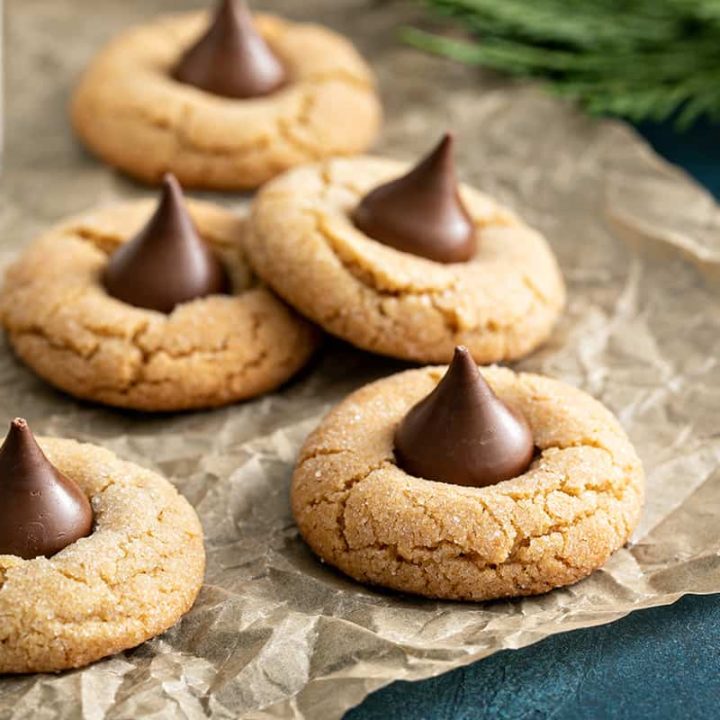 Peanut butter blossom cookies arranged on a piece of parchment paper next to a glass of milk