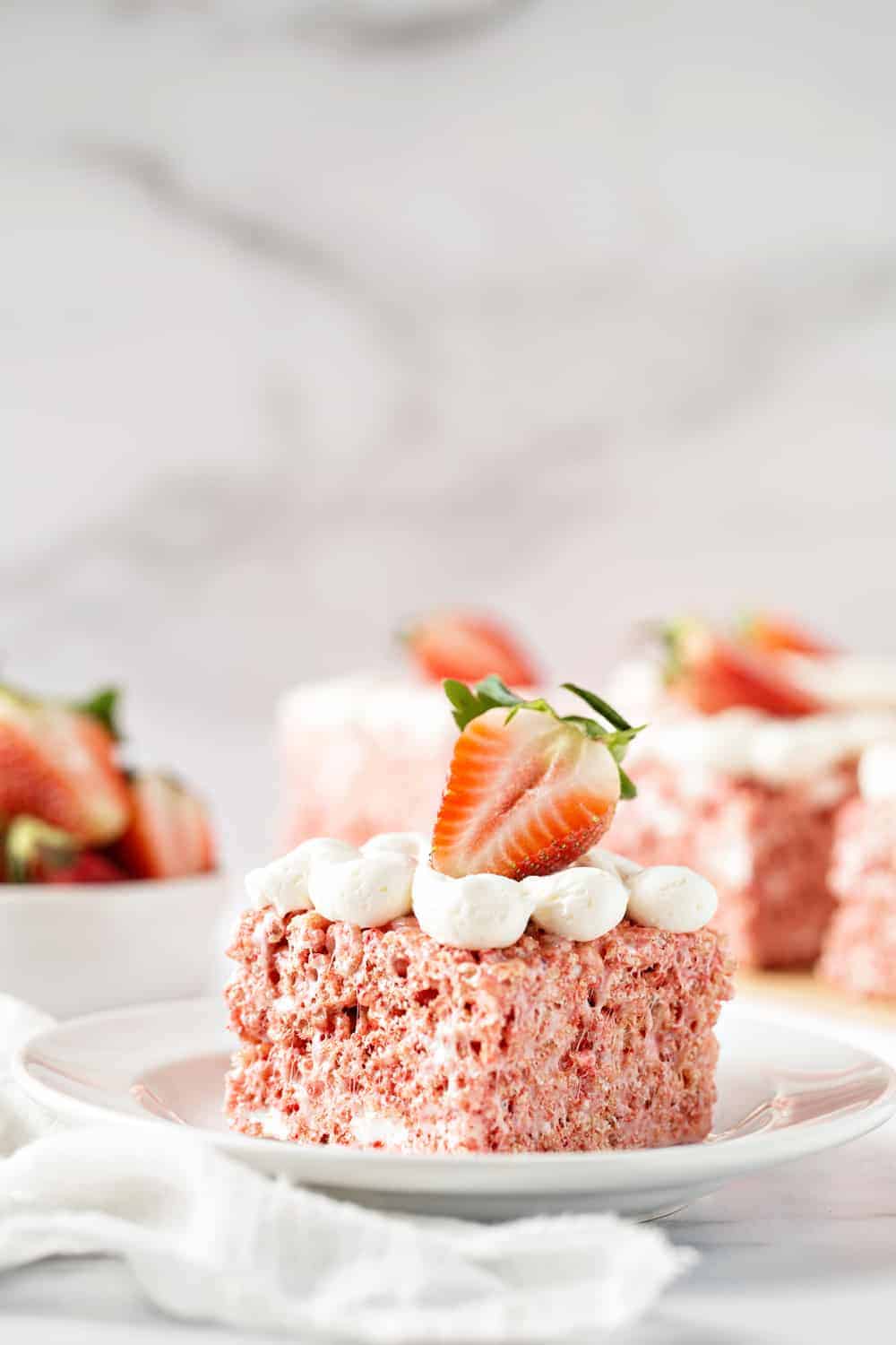 Strawberry Rice Krispie Treats are perfectly pink and full of fun strawberry flavor. Top them with pillowy buttercream frosting and fresh strawberries for an extra-special touch.