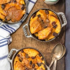 Overhead view of three ramekins of irish bread pudding. A small pitcher of whiskey caramel sauce is next to them.