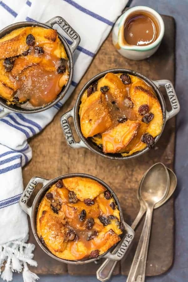 Overhead view of three ramekins of irish bread pudding. A small pitcher of whiskey caramel sauce is next to them.