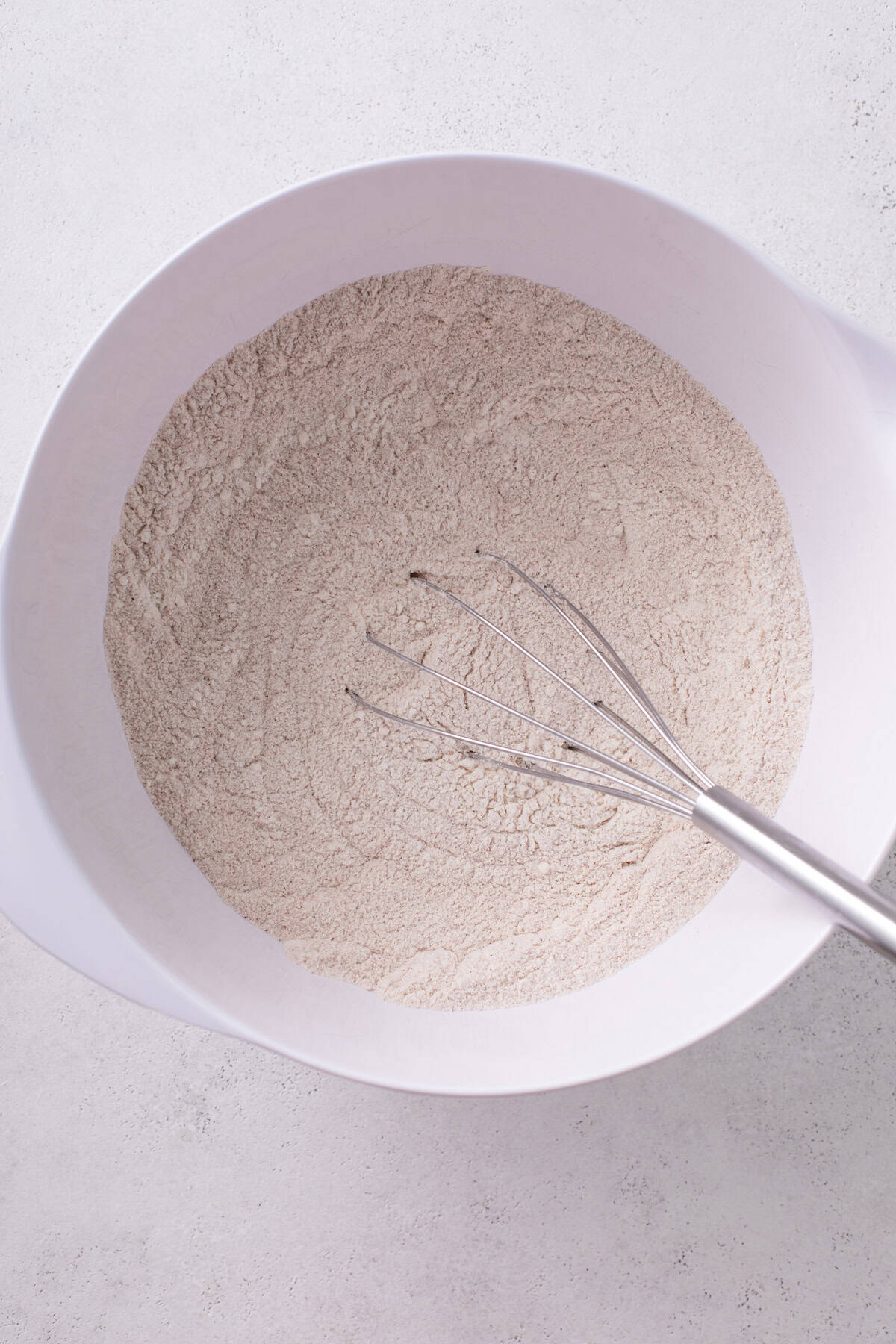 Dry ingredients for j alexander's carrot cake whisked in a white mixing bowl.