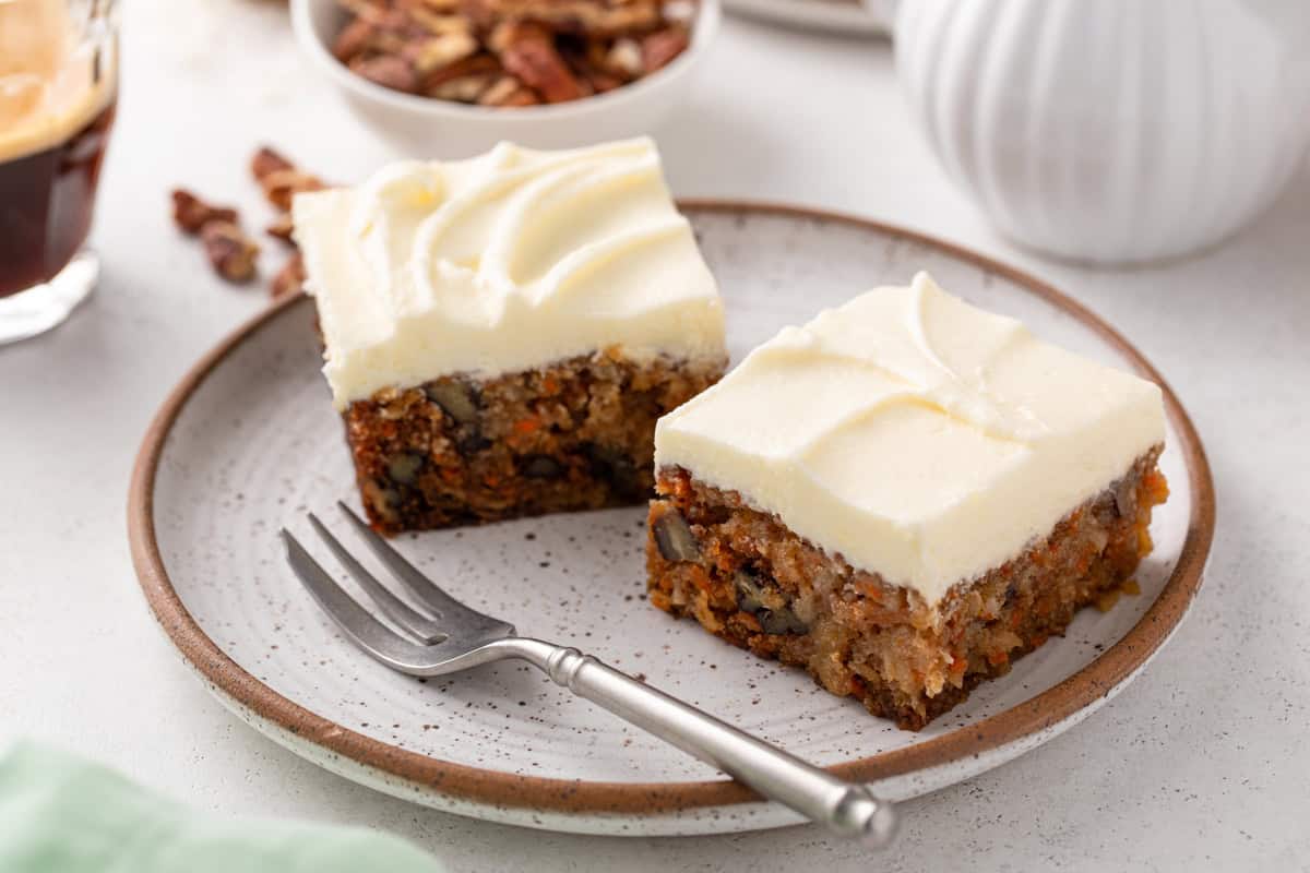 Two slices of j alexanders carrot cake next to each other on a plate.