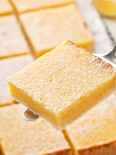 Sliced lemon bar being held up by a pie server.