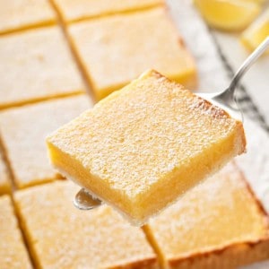 Sliced lemon bar being held up by a pie server.