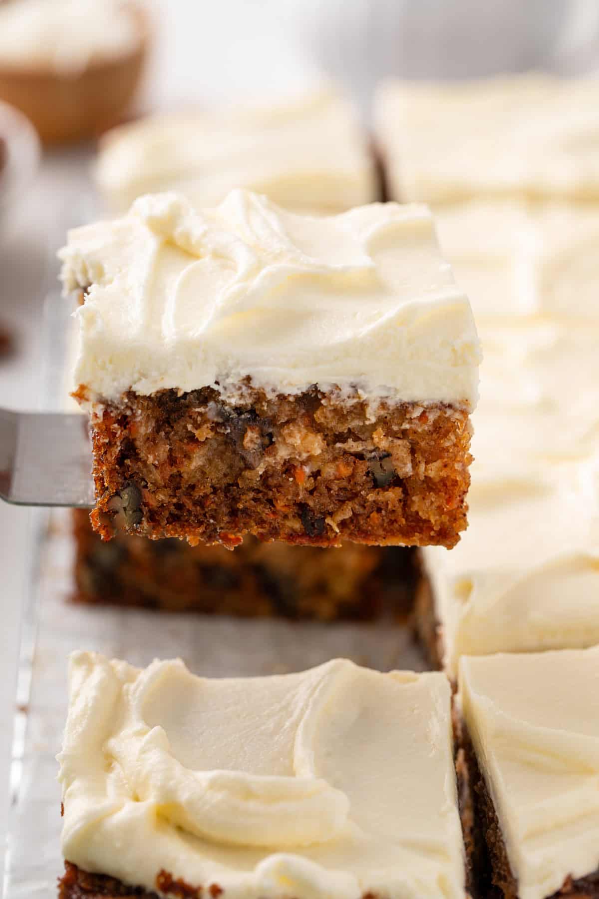 Cake server lifting up a slice of j alexander's carrot cake to serve it.