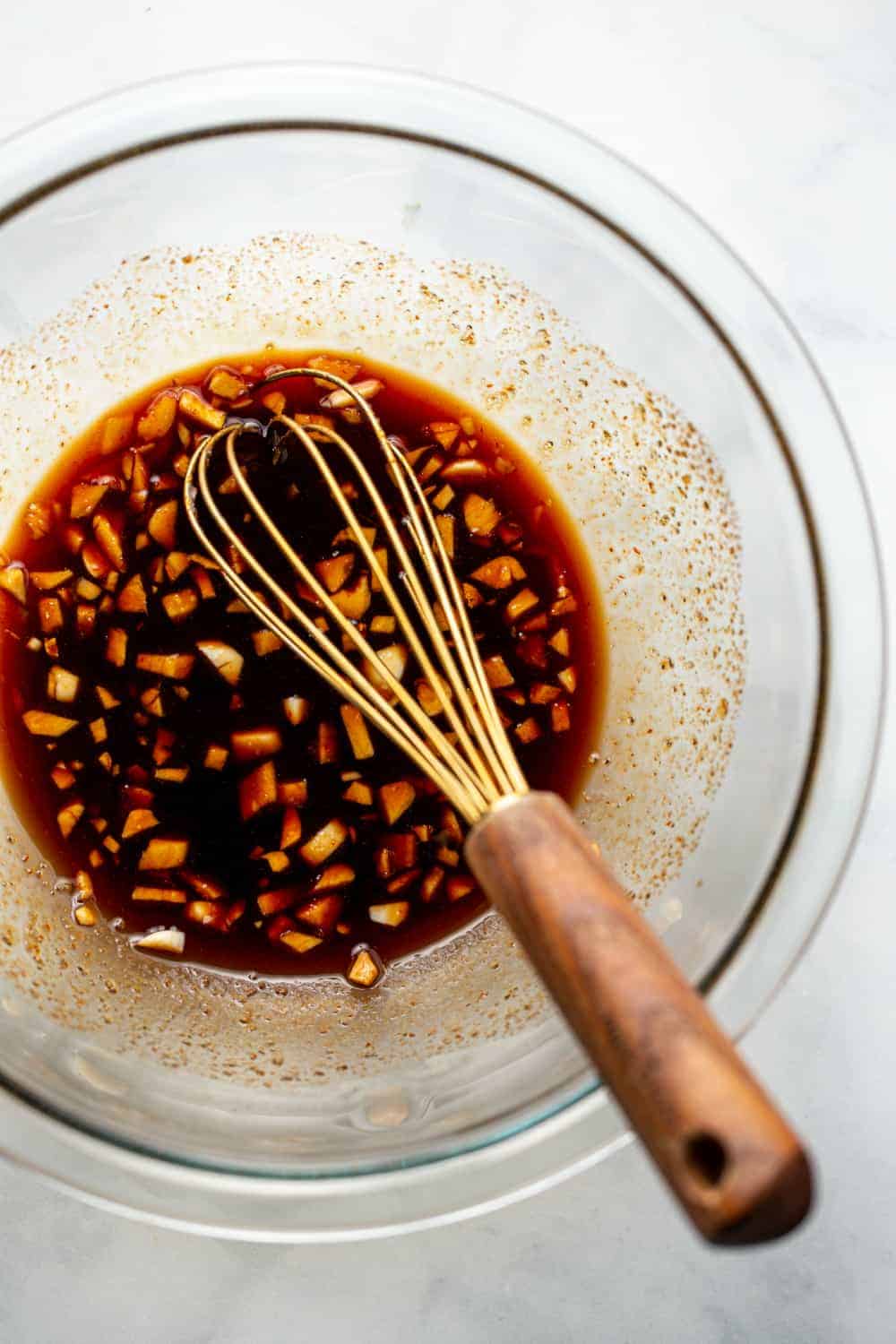 Sauce for honey soy chicken in a bowl with a whisk