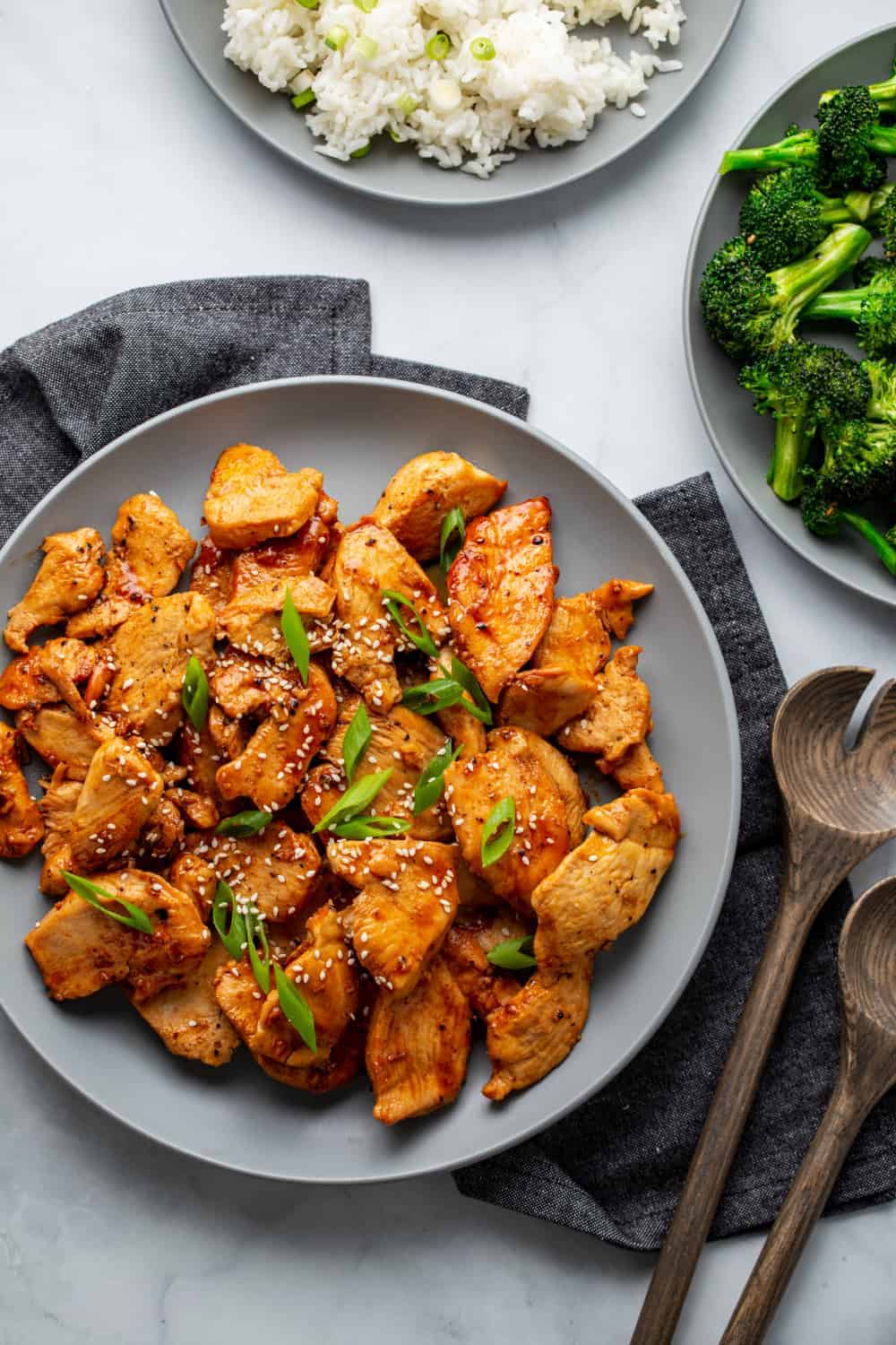 Honey soy chicken on a serving platter next to serving dishes of cooked broccoli and rice