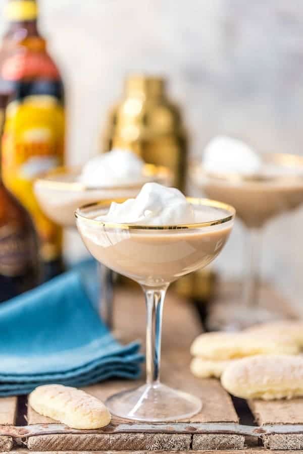 Side view of tiramisu martini in a gold-rimmed coupe glass topped with whipped cream