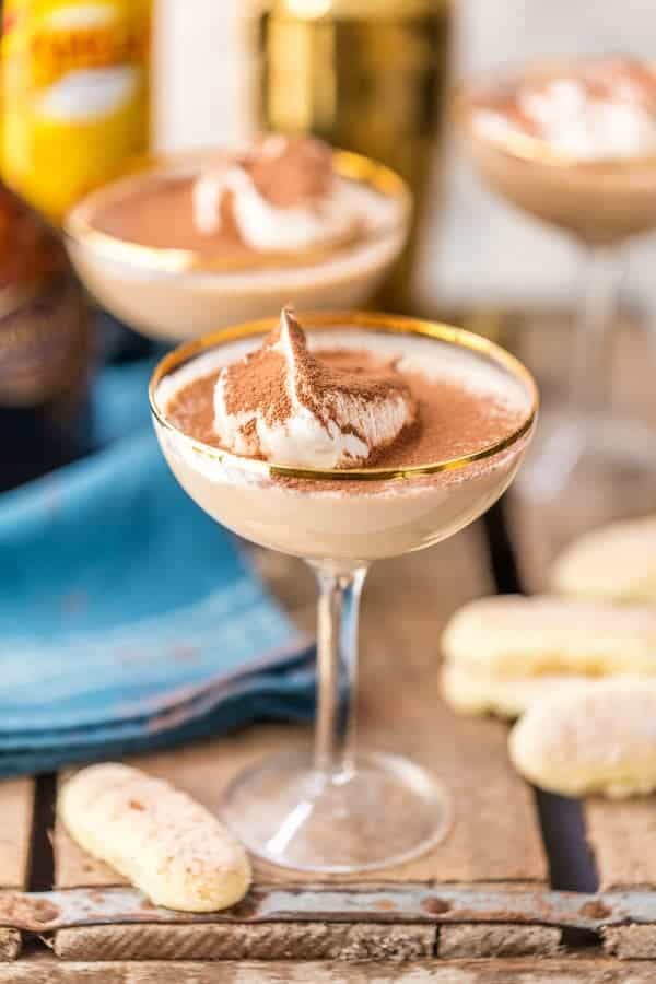 Tiramisu martini in a coupe glass dusted with cocoa powder, surrounded by ladyfinger cookies