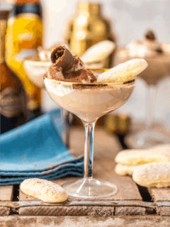 Side view of ladyfinger martini cocktail in a coupe glass on wood surface with blue napkin and ladyfinger cookies