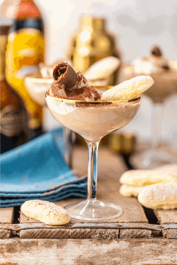 Side view of ladyfinger martini cocktail in a coupe glass on wood surface with blue napkin and ladyfinger cookies