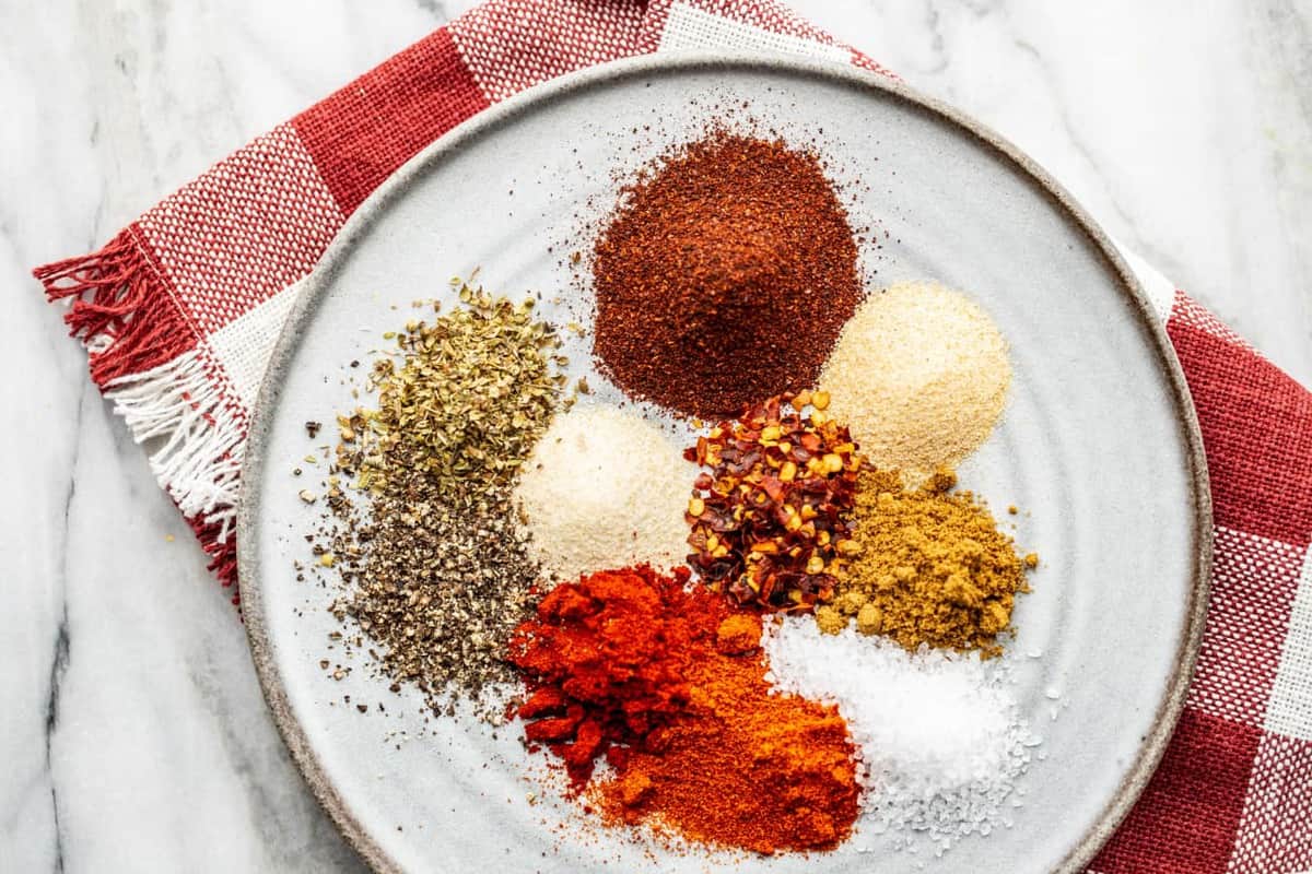 Spices for homemade taco seasoning on a plate with a red dish towel