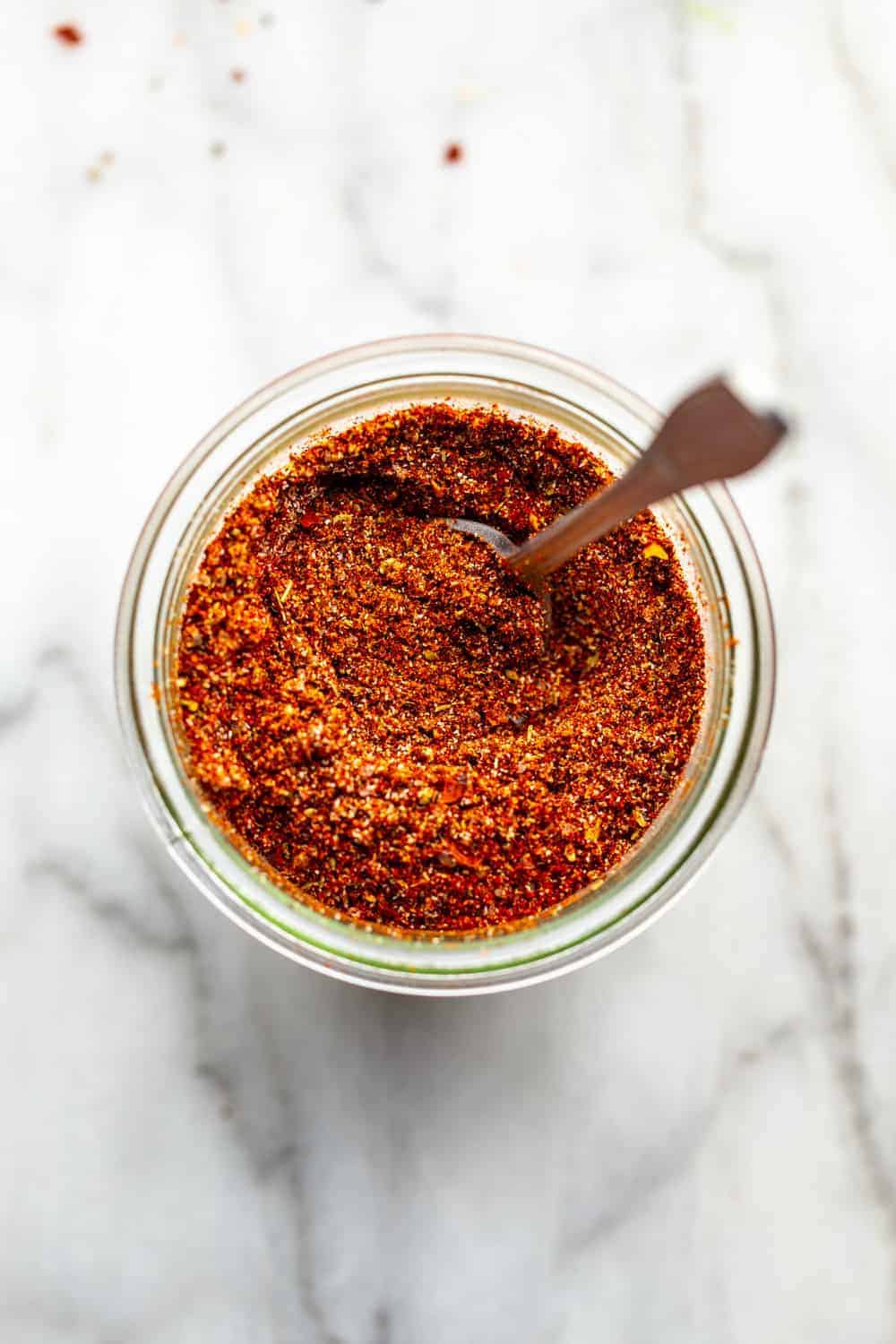 spoon mixing up a jar of homemade taco seasoning