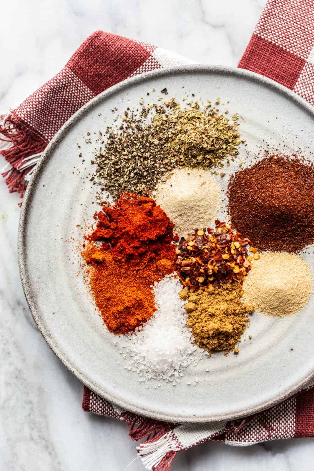 Overhead view of spices for homemade chili seasoning arranged on a plate