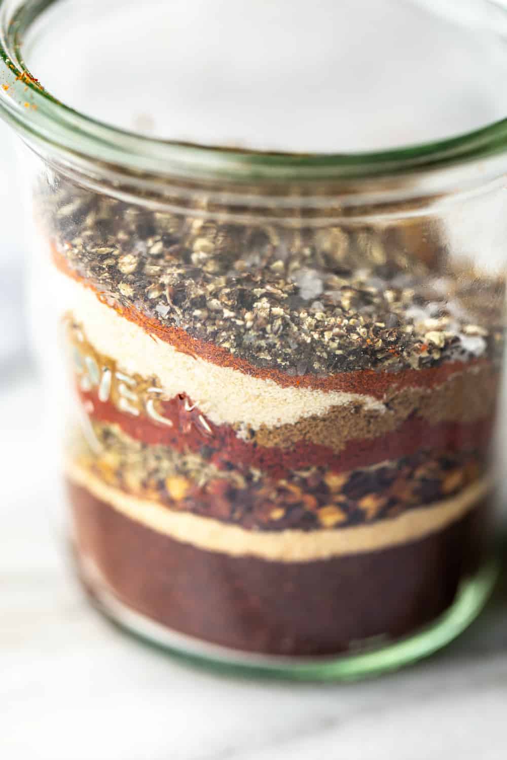 Side view of spices for homemade chili seasoning layered in a jar