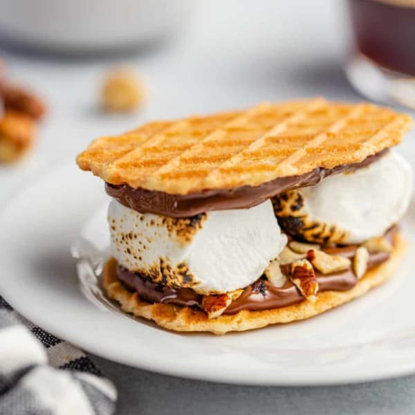 Plated s'more made with waffle cookies, chocolate hazelnut spread and 2 large roasted marshmallows