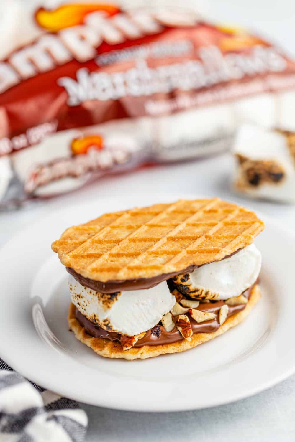 Toasted Hazelnut S'more made with waffle cookies with bag of marshmallows in the background