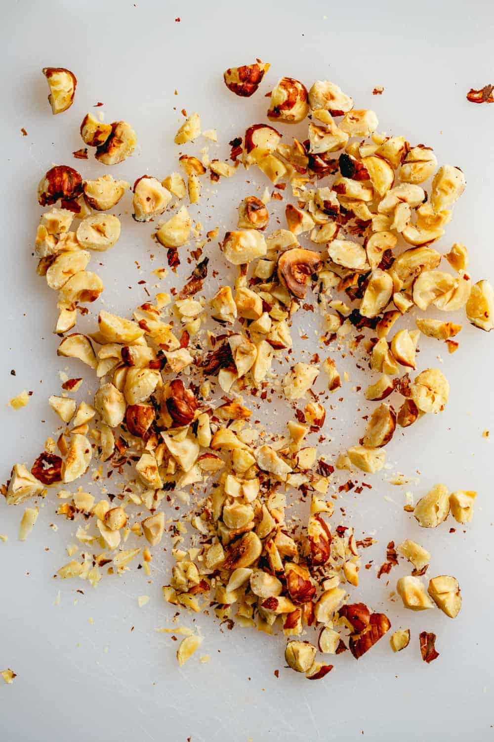 Chopped toasted hazelnuts on a white surface