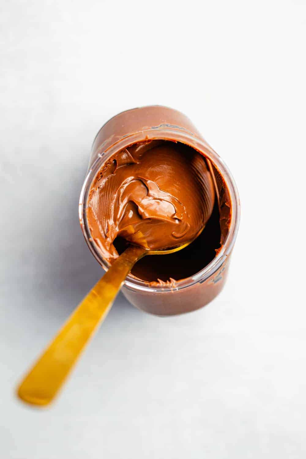 Overhead view of spoon in an open jar of chocolate hazelnut spread