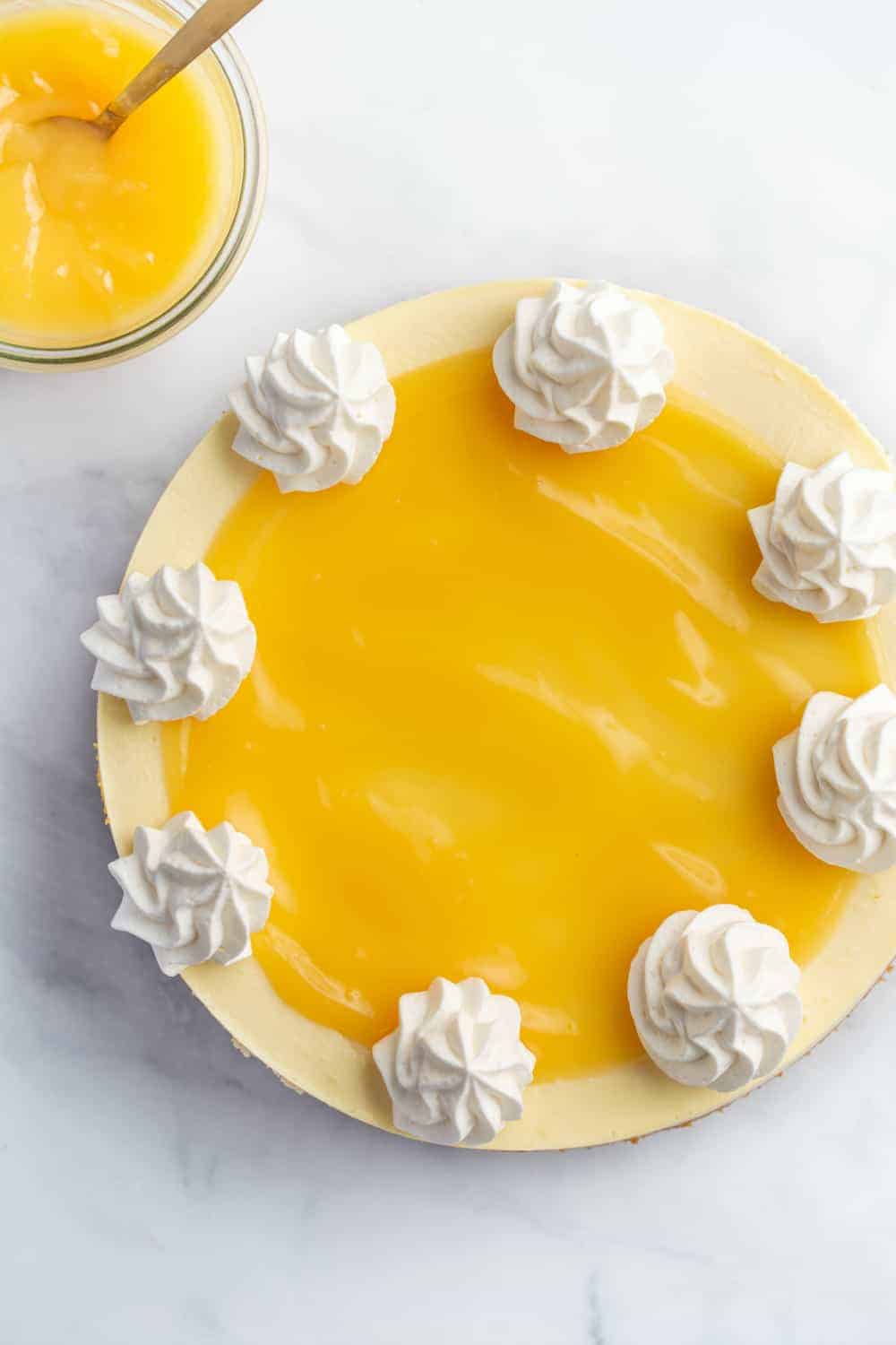 Overhead view of lemon cheesecake topped with lemon curd and whipped cream