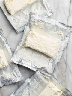 Unwrapped blocks of cream cheese on their wrappers