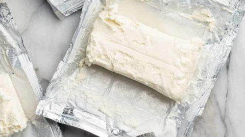 Unwrapped blocks of cream cheese on their wrappers