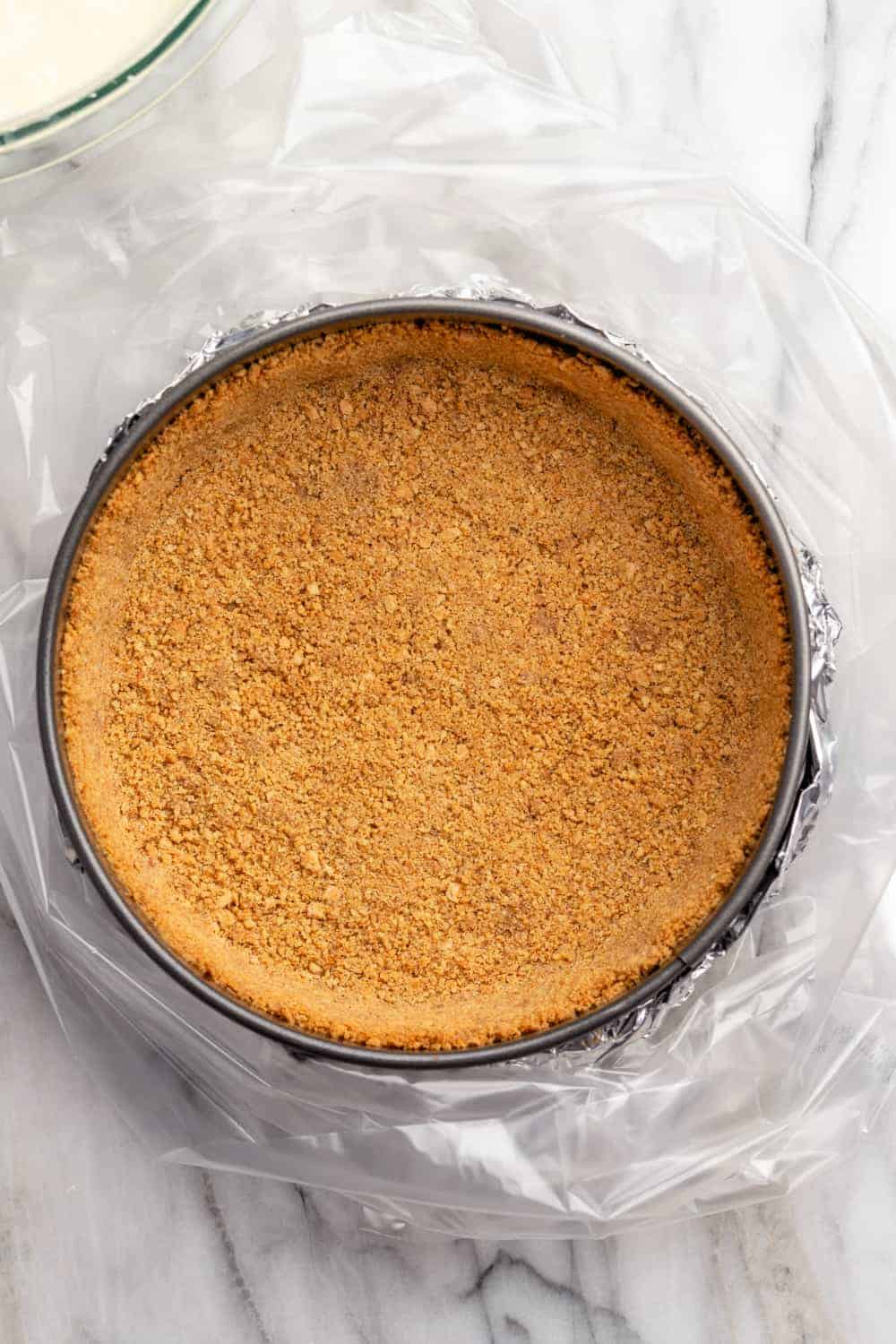 Baked graham cracker crust in a springform pan, ready to add cheesecake filling