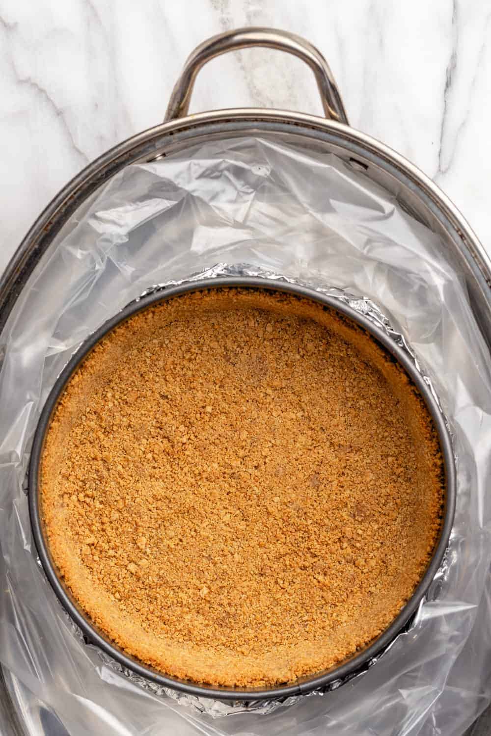 Graham cracker crust in a roasting pan, ready for filling and a water bath