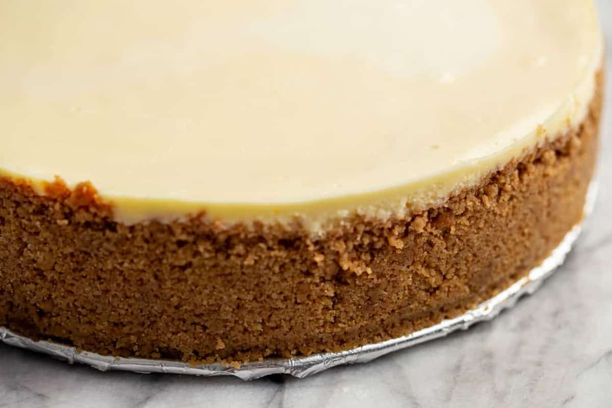 Close-up of baked graham cracker crust on a baked cheesecake