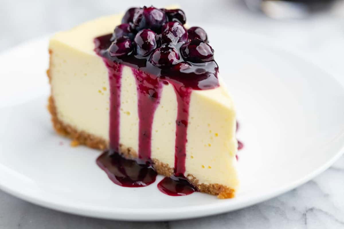 Slice of vanilla cheesecake topped with blueberry sauce