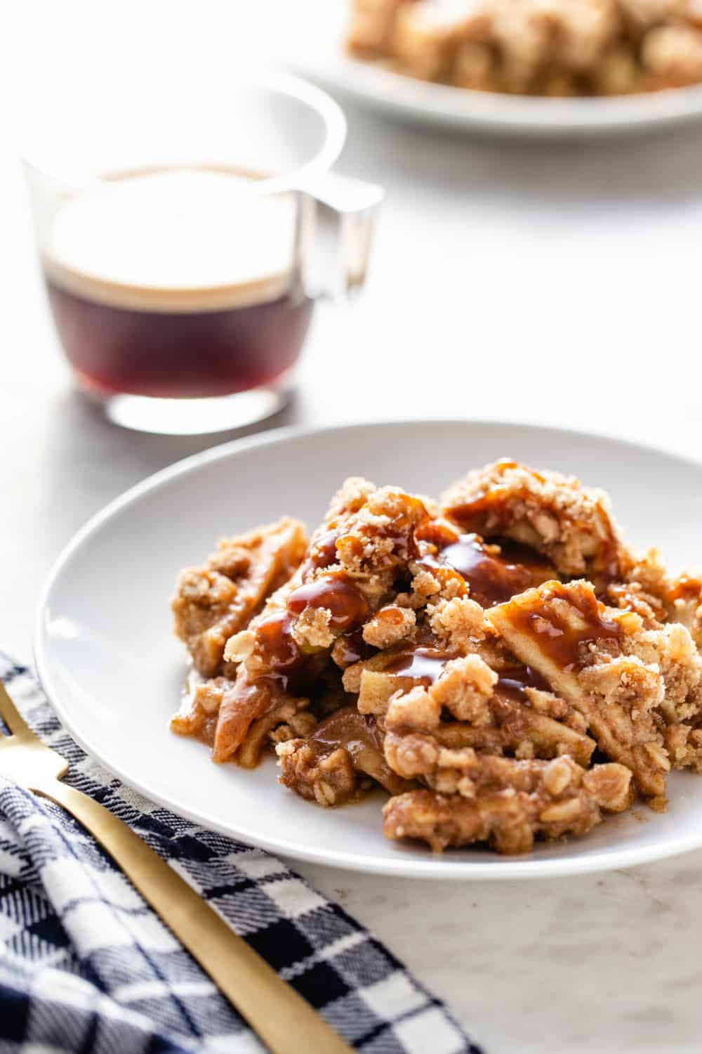 Plate of caramel apple crisp next to a cup of espresso