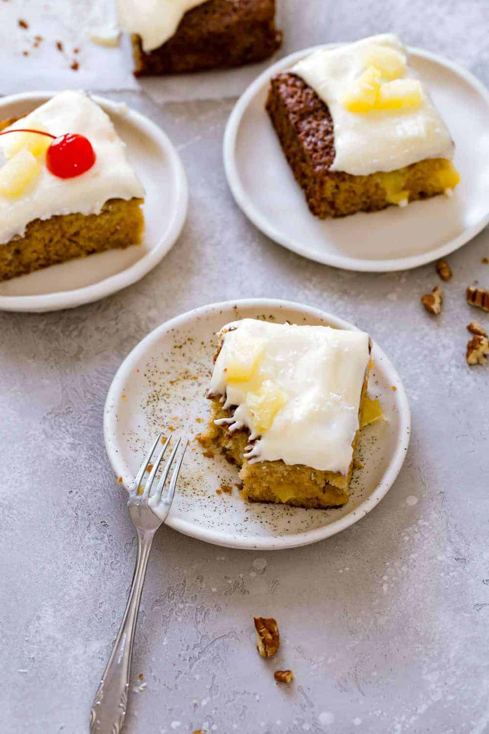 Slice of pineapple cake with topped with cream cheese frosting with a bite taken out of it