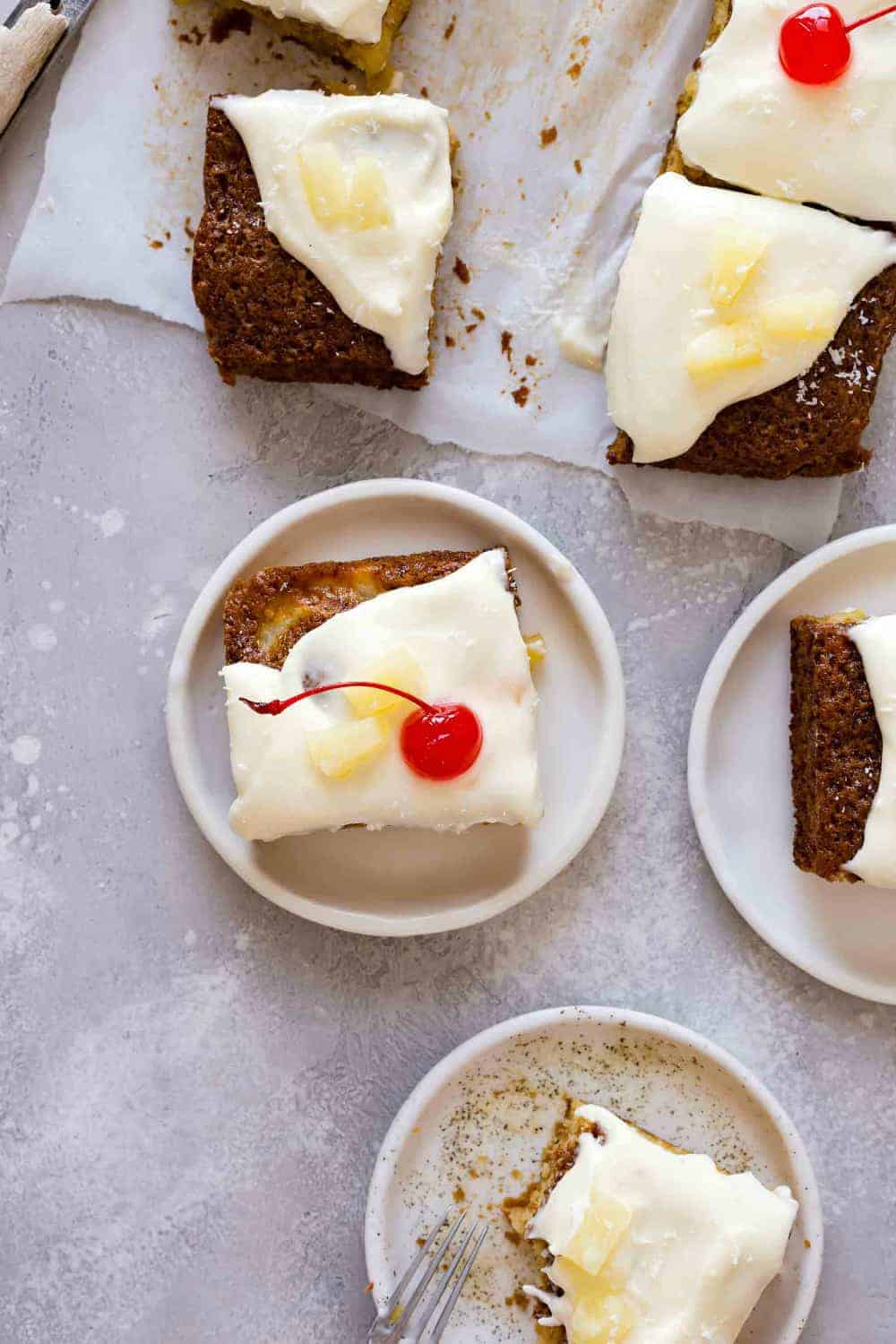 Plated slices of pineapple cake topped with cream cheese frosting