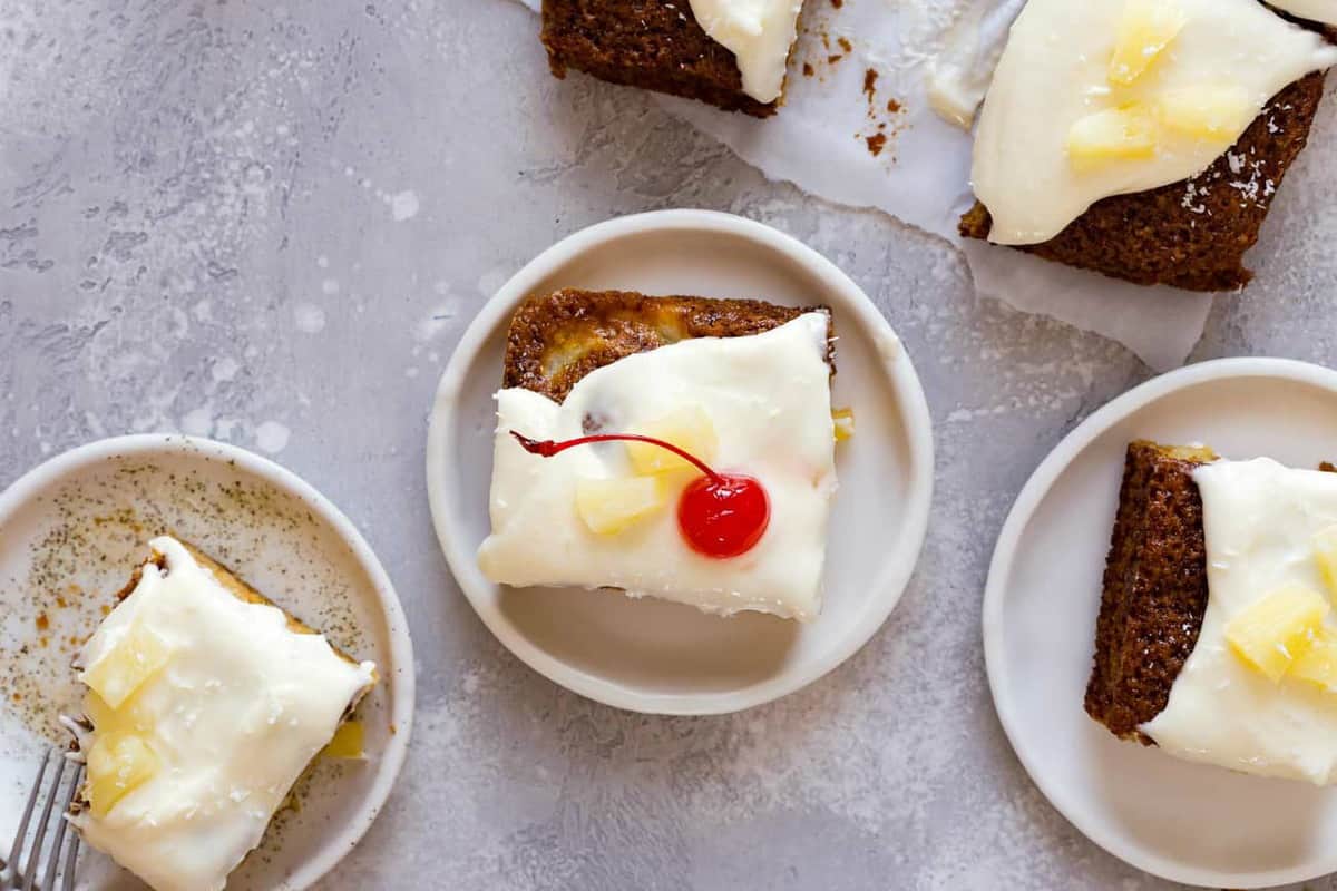 Overhead view of a slice of pineapple cake garnished with a maraschino cherry