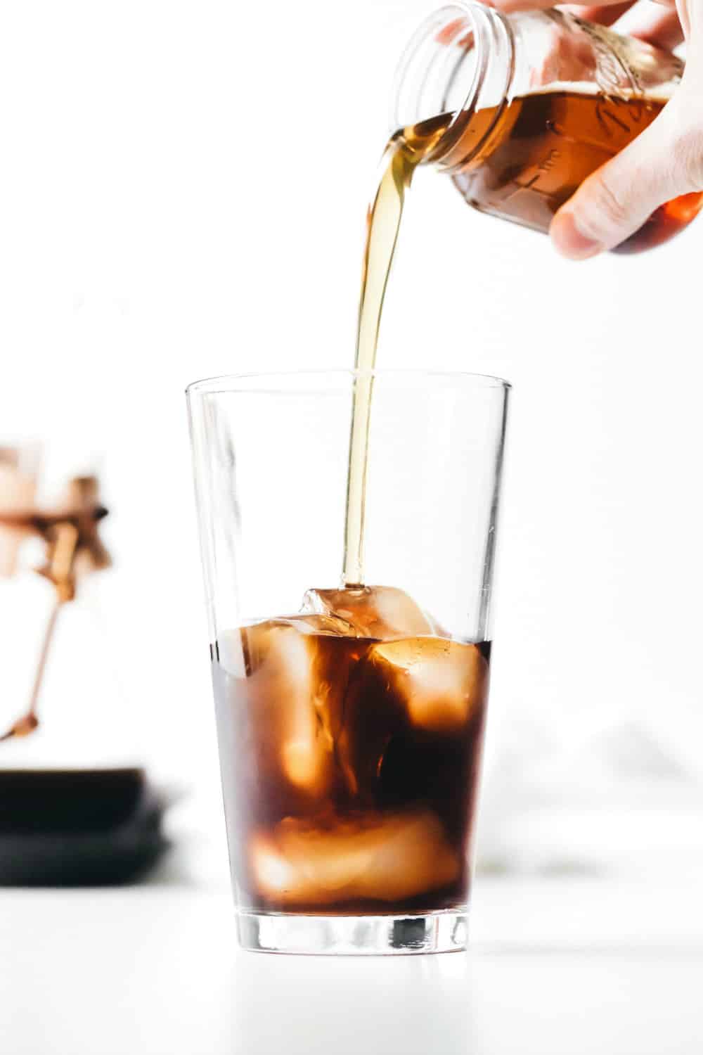 Adding vanilla coffee syrup to a glass of iced coffee