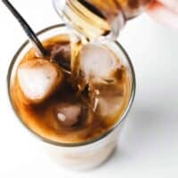 Adding vanilla coffee syrup to a glass of iced coffee