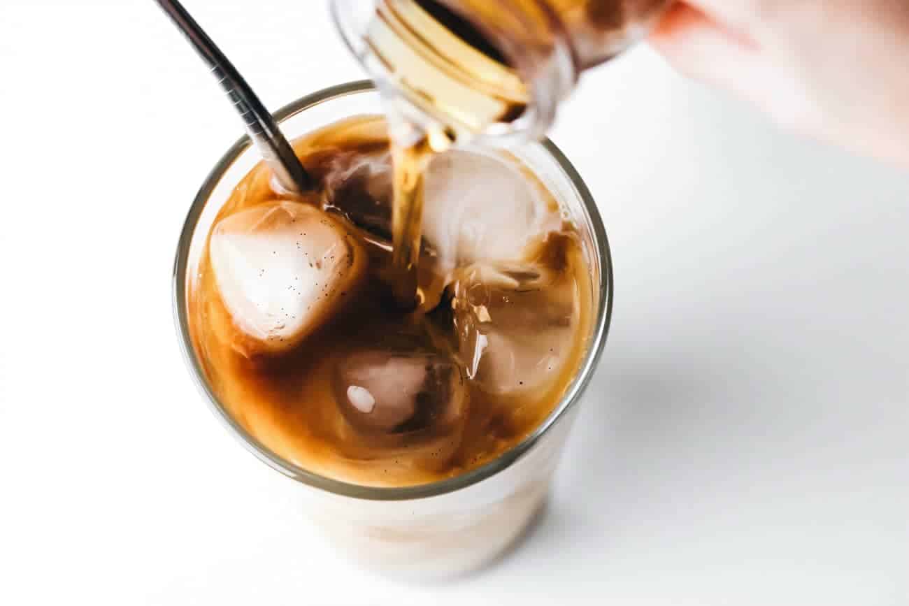 Adding vanilla coffee syrup to a glass of iced coffee