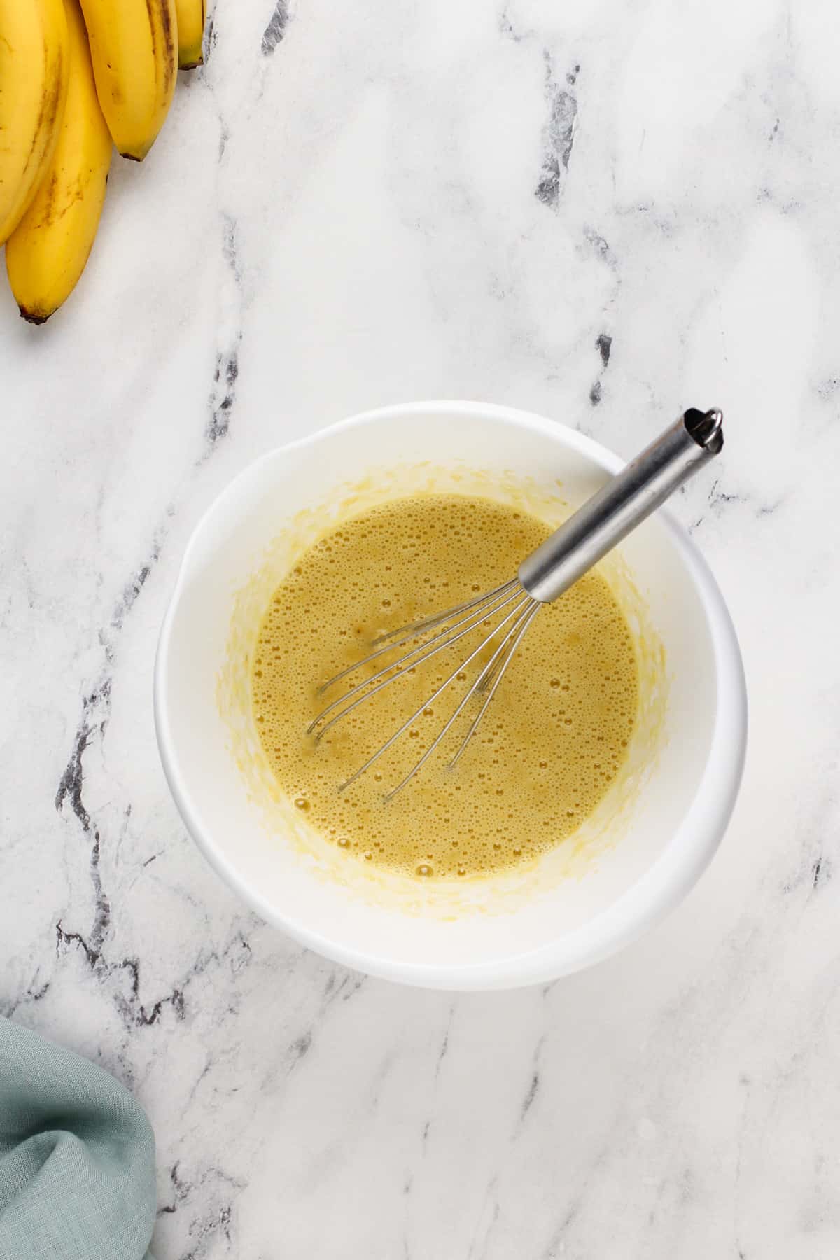 Mashed banana and eggs whisked together in a bowl.