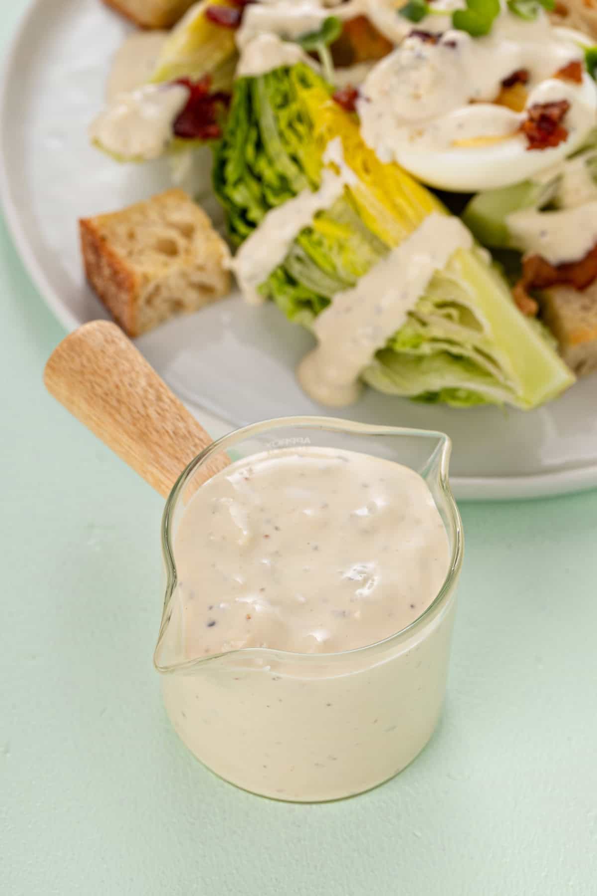 Glass jar for pouring salad dressing filled with blue cheese dressing.