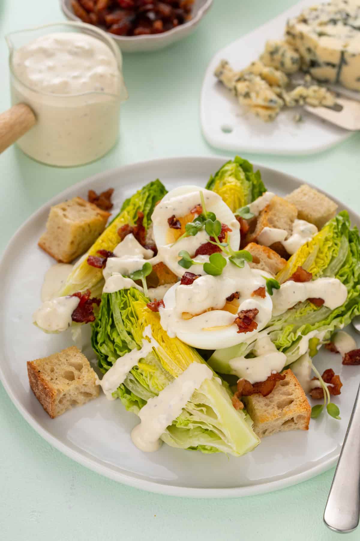 Green salad on a white plate, topped with homemade blue cheese dressing.