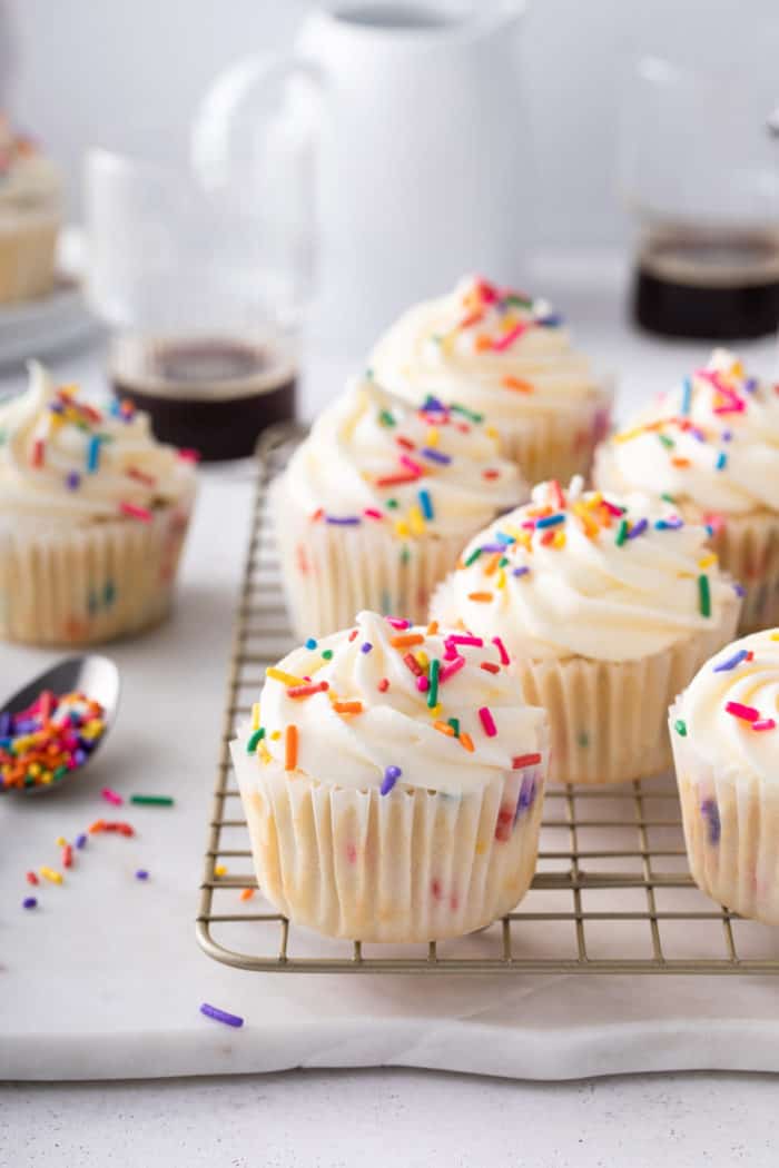 Frosted funfetti cupcakes arranged on a wire cooling rack.